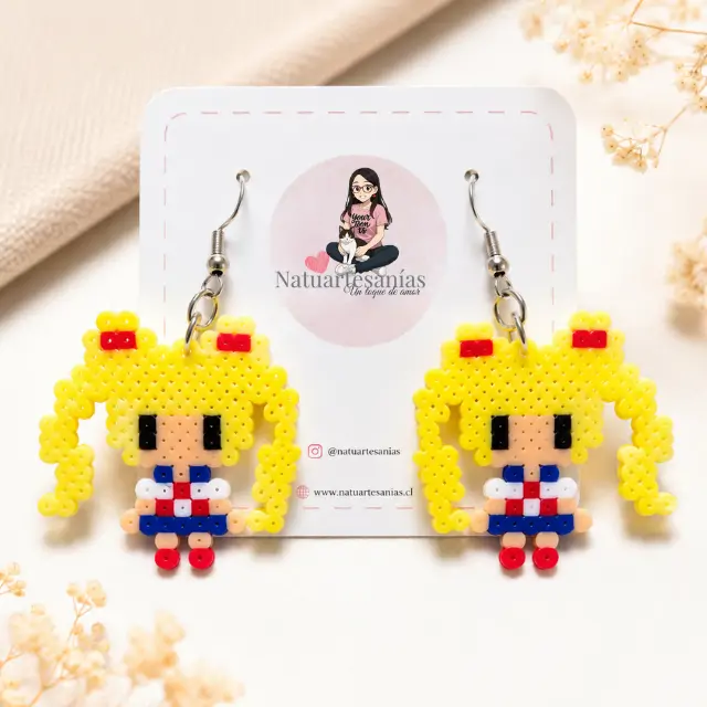 Aretes artesanales de Sailor Moon creados con Hama Beads, presentados sobre una base suave y elegante lista para regalar.